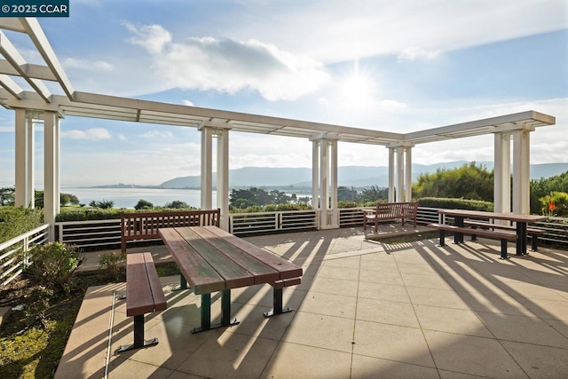 view of patio with a water and mountain view and a pergola