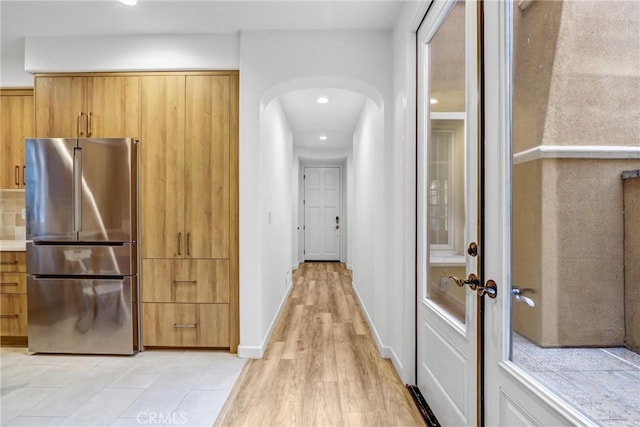 interior space featuring decorative backsplash, stainless steel fridge, french doors, and light hardwood / wood-style floors