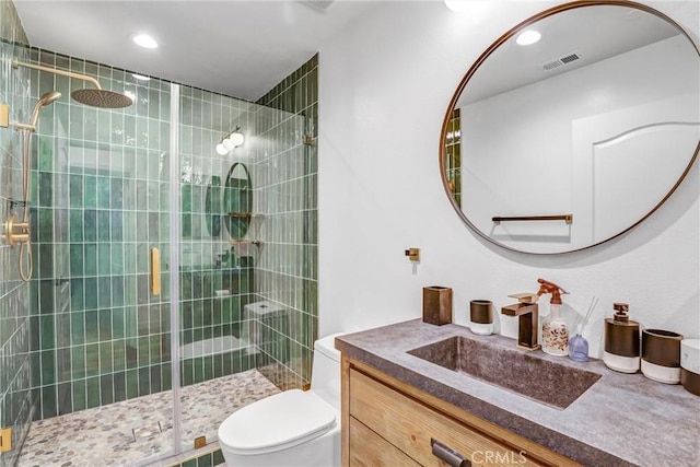 bathroom with a shower with shower door, toilet, and vanity