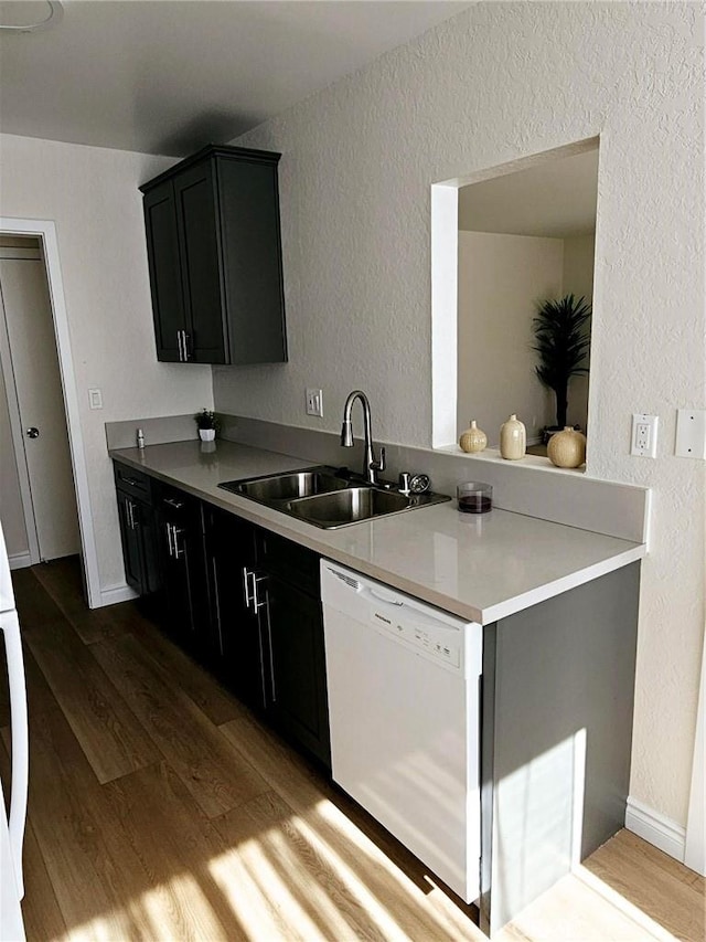 kitchen featuring white dishwasher, sink, hardwood / wood-style flooring, and kitchen peninsula