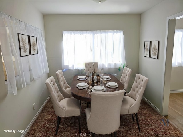 dining area with wood finished floors, a wealth of natural light, and baseboards