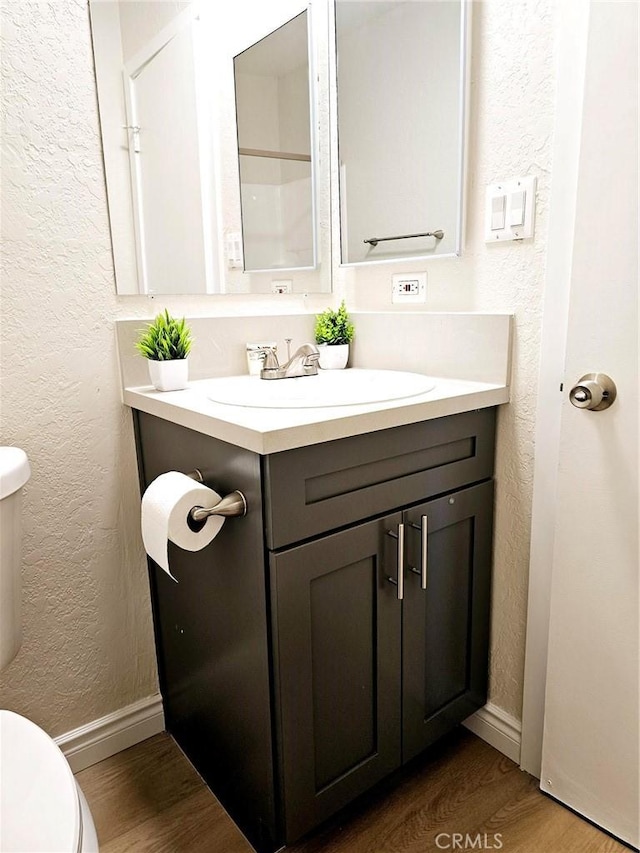 bathroom featuring toilet, vanity, and hardwood / wood-style floors