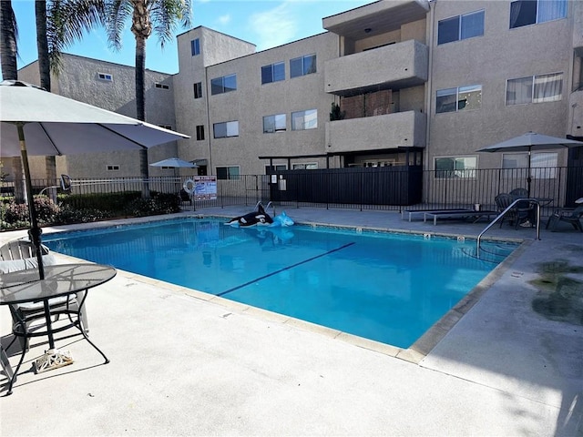 community pool with fence and a patio