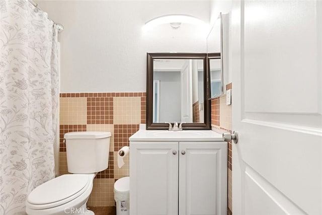 bathroom featuring curtained shower, tile walls, toilet, and vanity