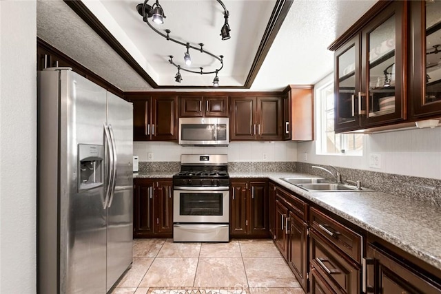 kitchen with stainless steel appliances, sink, a raised ceiling, light tile patterned flooring, and dark brown cabinets