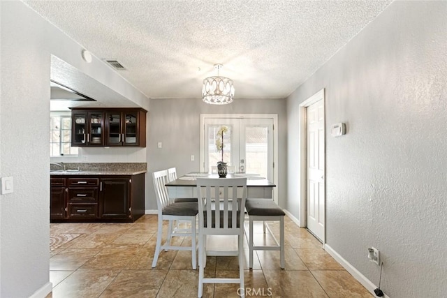 dining room with sink, a textured ceiling, and a chandelier