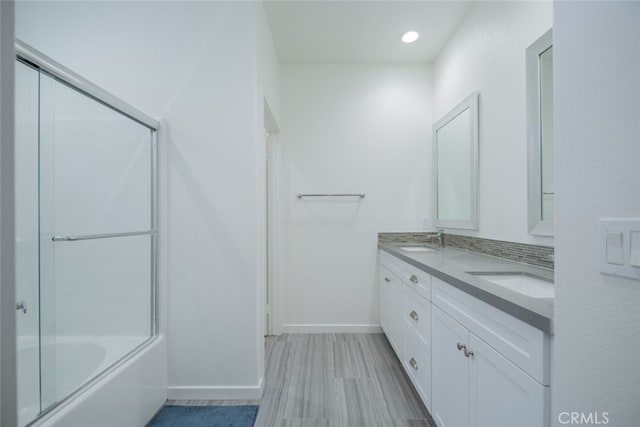 bathroom featuring decorative backsplash, bath / shower combo with glass door, vanity, and hardwood / wood-style floors