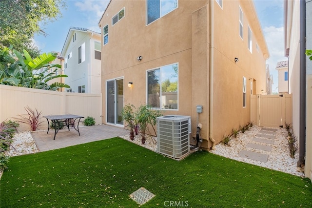 rear view of house featuring a yard, a patio, and central air condition unit