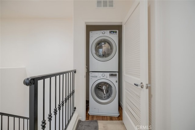 laundry area featuring hardwood / wood-style flooring and stacked washer and clothes dryer