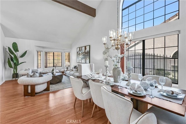 dining room with high vaulted ceiling, a chandelier, beamed ceiling, and light wood-type flooring