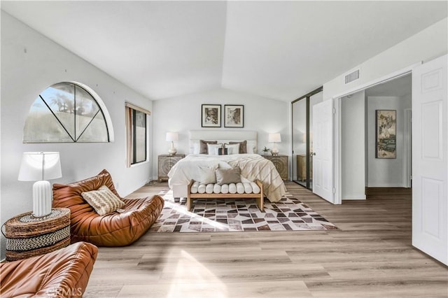 bedroom with lofted ceiling and light wood-type flooring