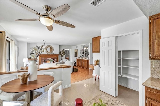 dining space featuring ceiling fan, light tile patterned floors, and a fireplace