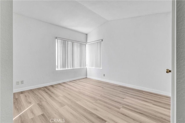 spare room featuring lofted ceiling and light wood-type flooring