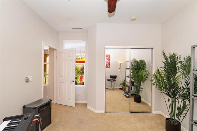 interior space with ceiling fan and light colored carpet