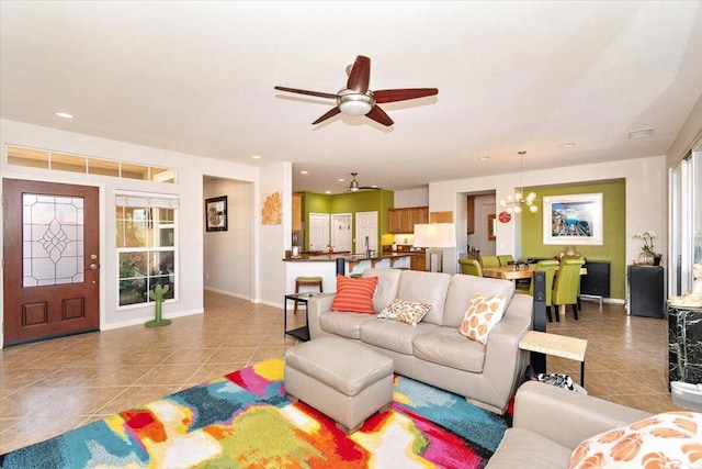 living room featuring ceiling fan with notable chandelier and light tile patterned floors