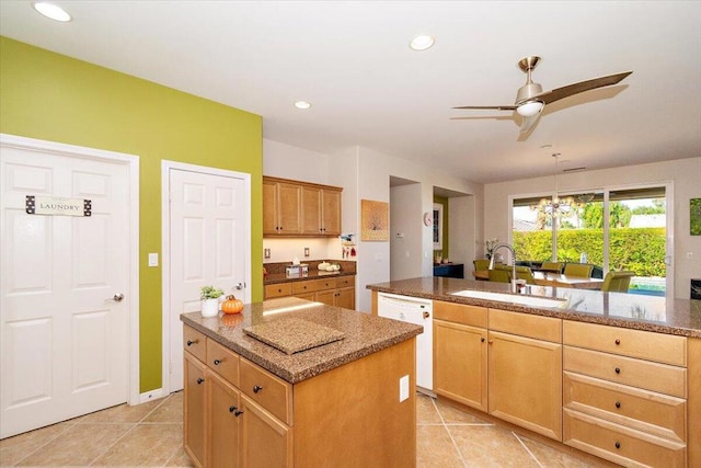 kitchen featuring light tile patterned floors, sink, dishwasher, and an island with sink