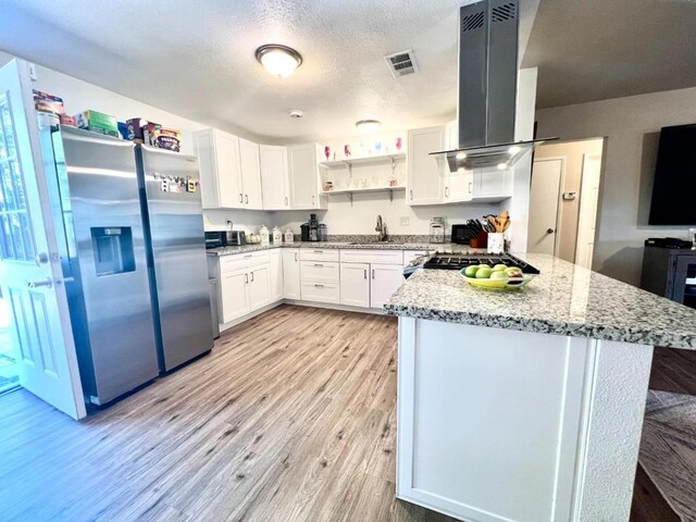 kitchen with white cabinets, island exhaust hood, stainless steel appliances, sink, and light stone counters