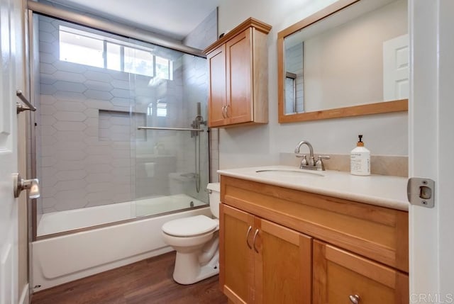 full bathroom with toilet, vanity, shower / bath combination with glass door, and hardwood / wood-style flooring