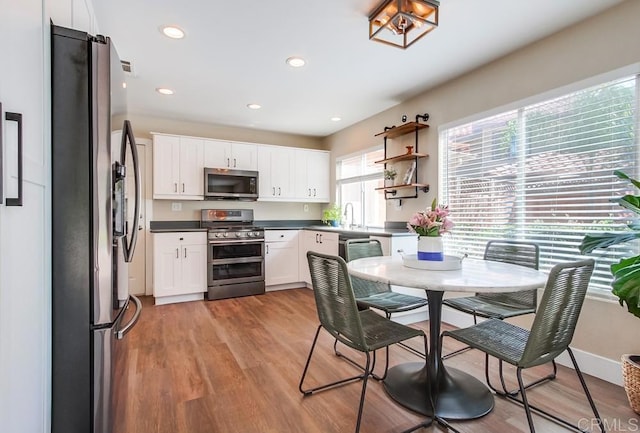 kitchen with light wood-type flooring, appliances with stainless steel finishes, and white cabinets