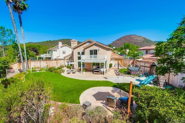 rear view of house featuring a mountain view, a lawn, outdoor lounge area, a balcony, and a patio