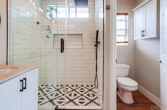 bathroom with toilet, hardwood / wood-style flooring, a shower with door, and vanity