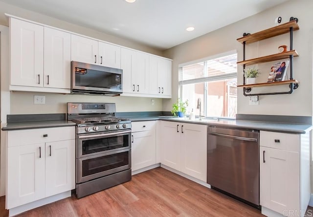 kitchen featuring appliances with stainless steel finishes, sink, white cabinetry, and light hardwood / wood-style floors