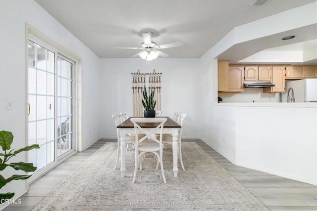 dining space with ceiling fan and light hardwood / wood-style floors