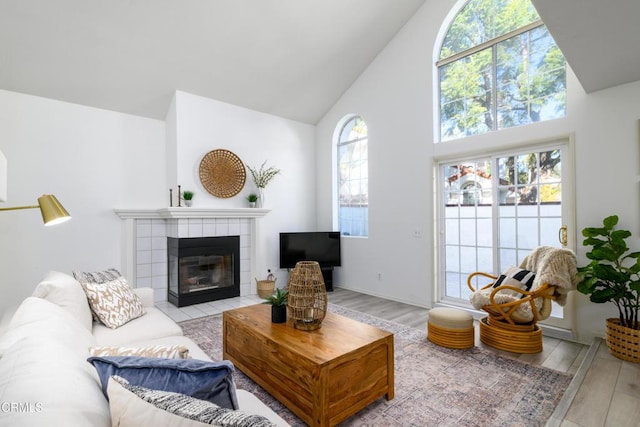 living room with high vaulted ceiling, a healthy amount of sunlight, a fireplace, and light hardwood / wood-style flooring