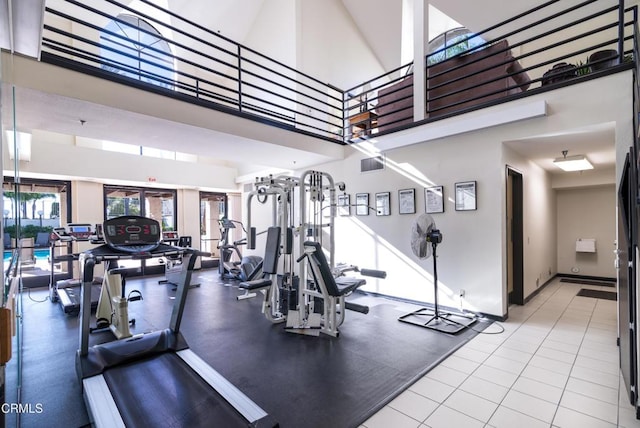 gym featuring light tile patterned flooring and a high ceiling