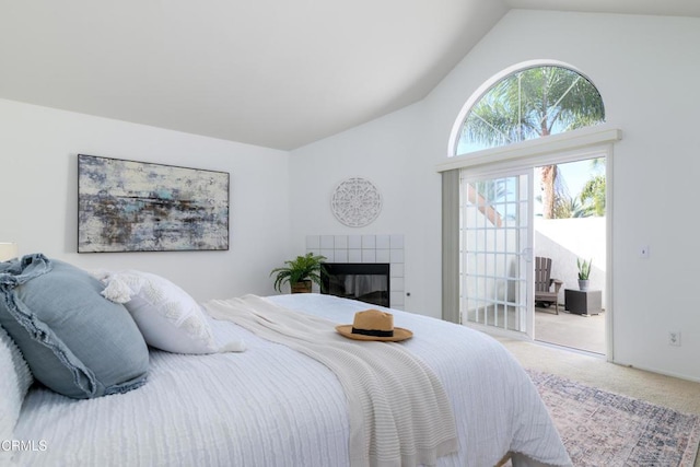 carpeted bedroom featuring a tile fireplace and vaulted ceiling