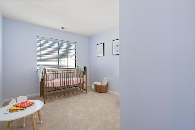 bedroom featuring light carpet and a nursery area