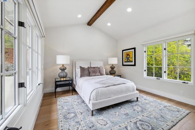 bedroom with vaulted ceiling with beams and light wood-type flooring