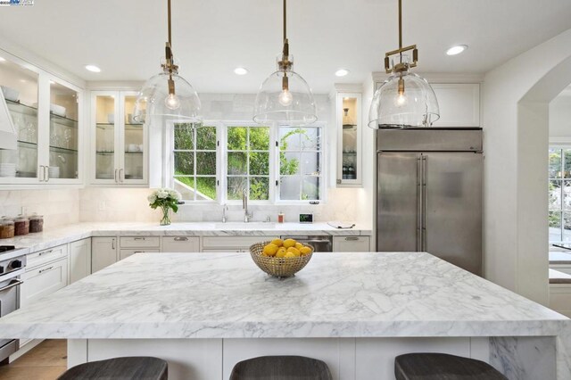 kitchen featuring white cabinets, a kitchen bar, backsplash, and pendant lighting