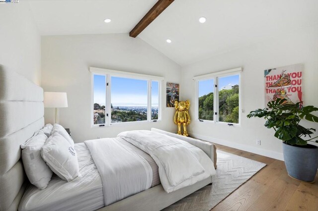 bedroom with lofted ceiling with beams, multiple windows, and hardwood / wood-style flooring