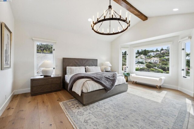 bedroom featuring lofted ceiling with beams, a notable chandelier, and light hardwood / wood-style floors