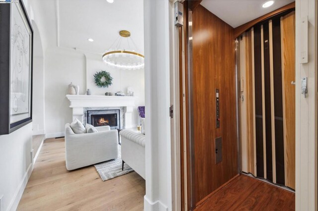 hallway with light hardwood / wood-style floors and elevator