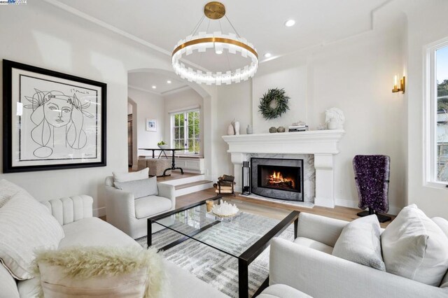 living room with a high end fireplace, ornamental molding, and hardwood / wood-style flooring