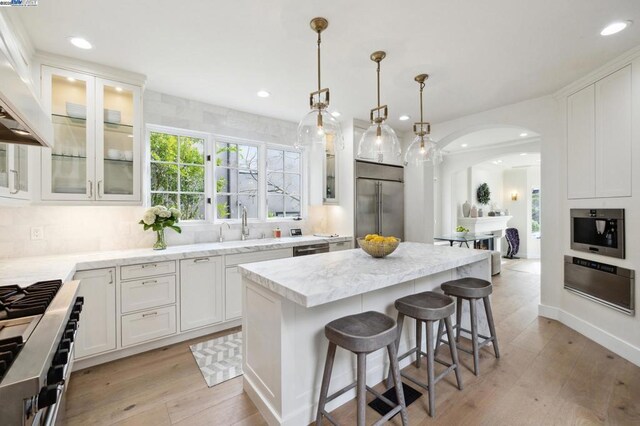 kitchen featuring decorative light fixtures, white cabinetry, a center island, and stainless steel appliances