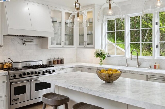 kitchen with white cabinetry, backsplash, and range with two ovens