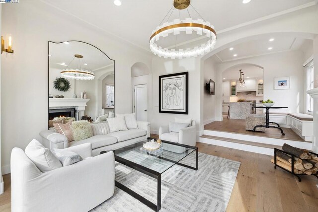 living room featuring crown molding, a notable chandelier, and light wood-type flooring