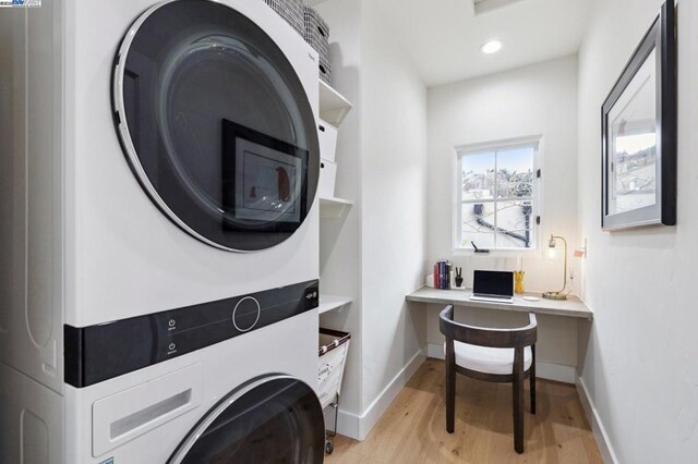 laundry area with stacked washer and clothes dryer and light hardwood / wood-style floors