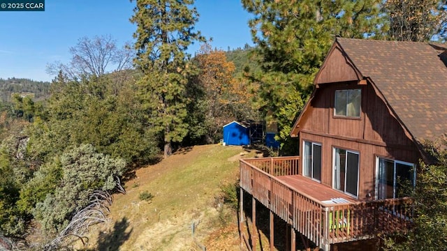 view of yard featuring a wooden deck and a storage shed