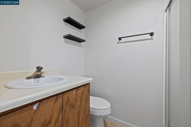 bathroom featuring toilet, vanity, and tile patterned flooring