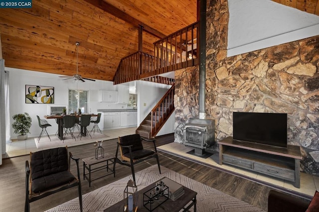 living room featuring wooden ceiling, ceiling fan, a wood stove, wood-type flooring, and high vaulted ceiling