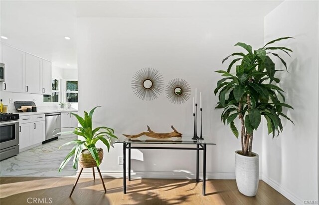 kitchen with white cabinets, appliances with stainless steel finishes, light hardwood / wood-style flooring, and sink