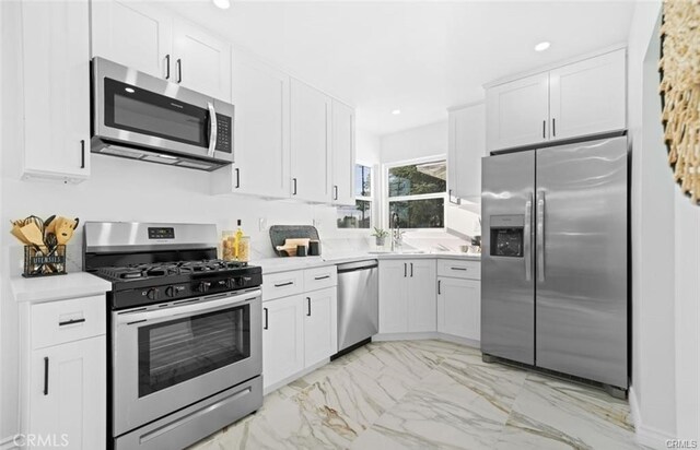 kitchen with appliances with stainless steel finishes, white cabinetry, and sink