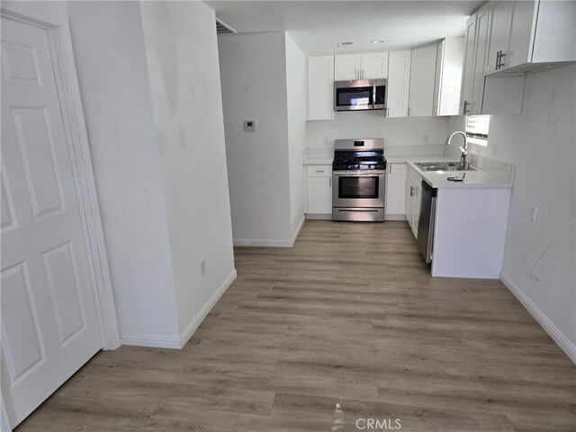 kitchen featuring light hardwood / wood-style flooring, stainless steel appliances, white cabinetry, and sink