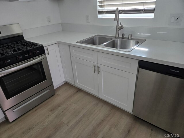 kitchen with sink, white cabinets, light hardwood / wood-style floors, and appliances with stainless steel finishes