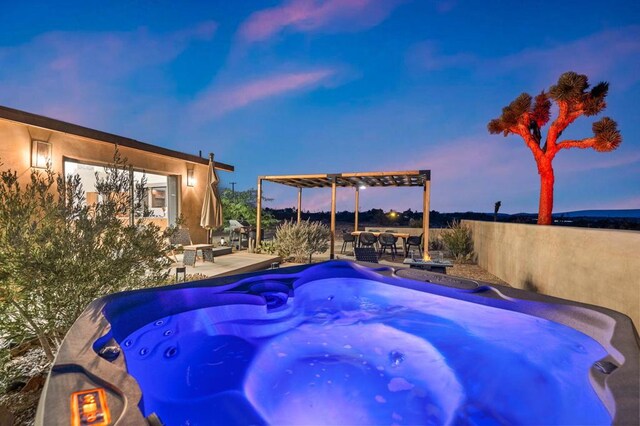 pool at dusk with a hot tub, a pergola, and a patio