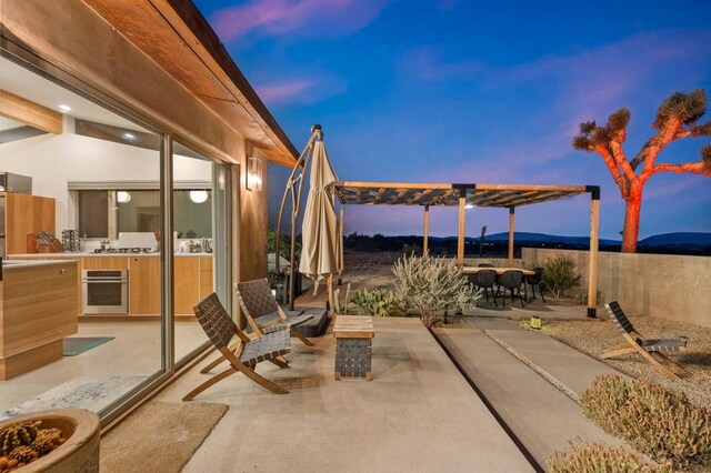 patio terrace at dusk featuring a mountain view and a pergola